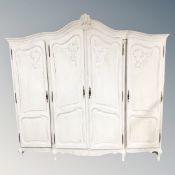 A Continental four door painted white armoire,