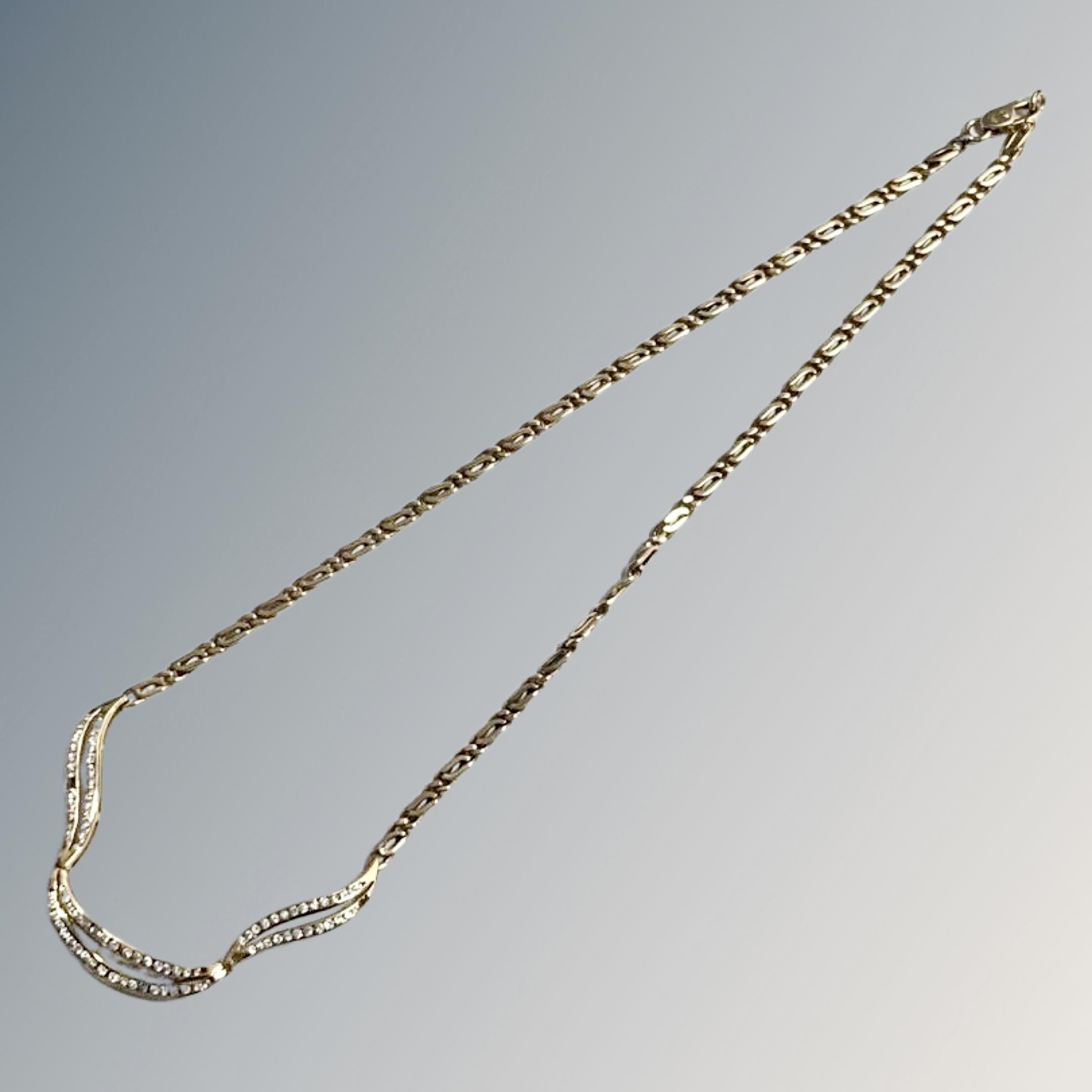 An 18ct yellow gold figaro type link necklace with three curved sections set with diamonds,