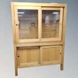 A contemporary oak double sliding door display cabinet fitted cupboards beneath on raised legs