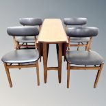 A teak drop leaf table together with a set of four black vinyl dining chairs