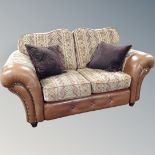 A tan leather and cloth two seater settee with scatter cushions