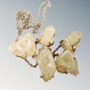 A yellow rough crystal necklace on a yellow metal chain with claw settings