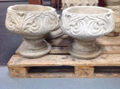 A pair of circular concrete planters on stands