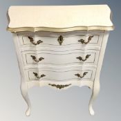 A reproduction serpentine fronted cream and gilt chest
