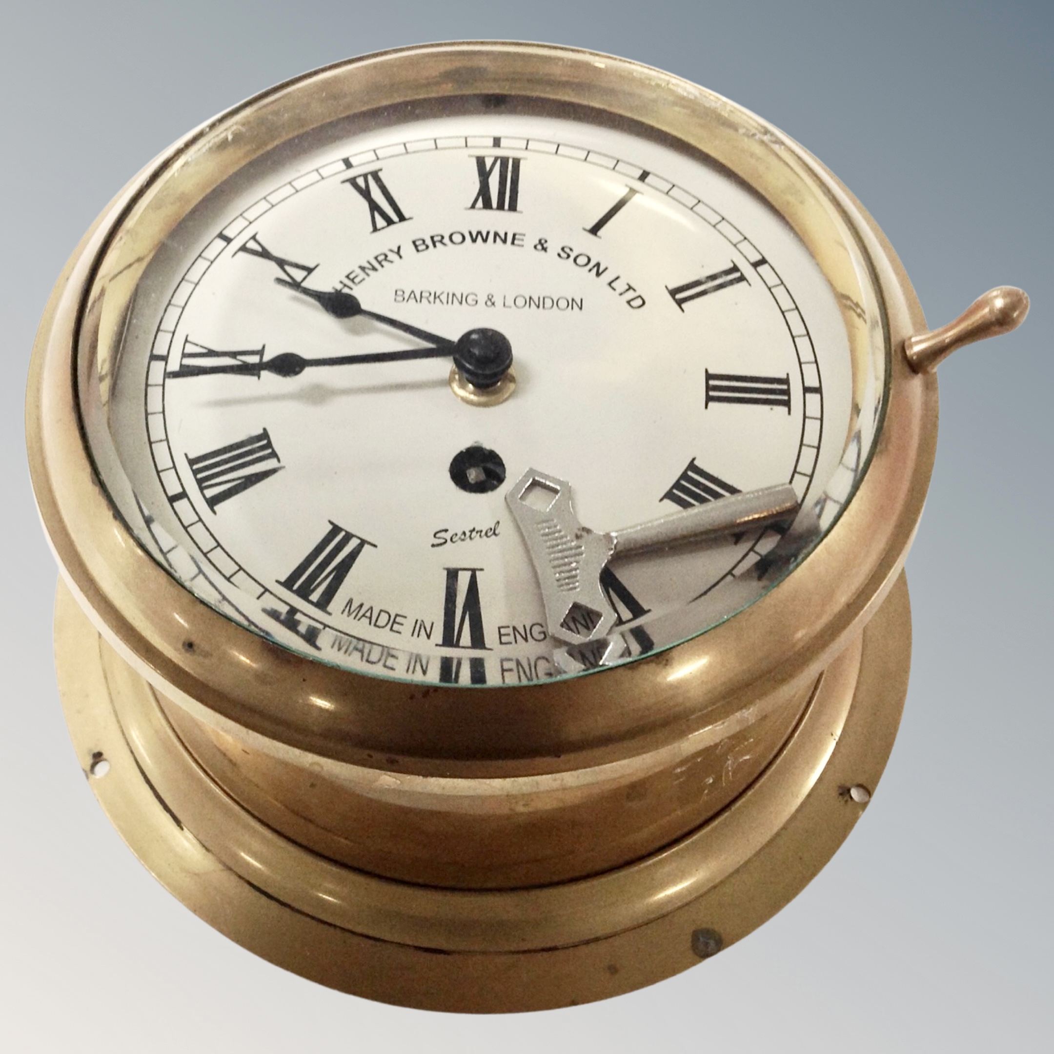 A brass ships clock with key by Henry Browne and Son.