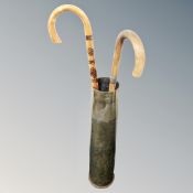 A large brass ammunition shell casing together with two walking sticks.