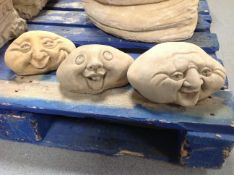 Three concrete happy face ornaments