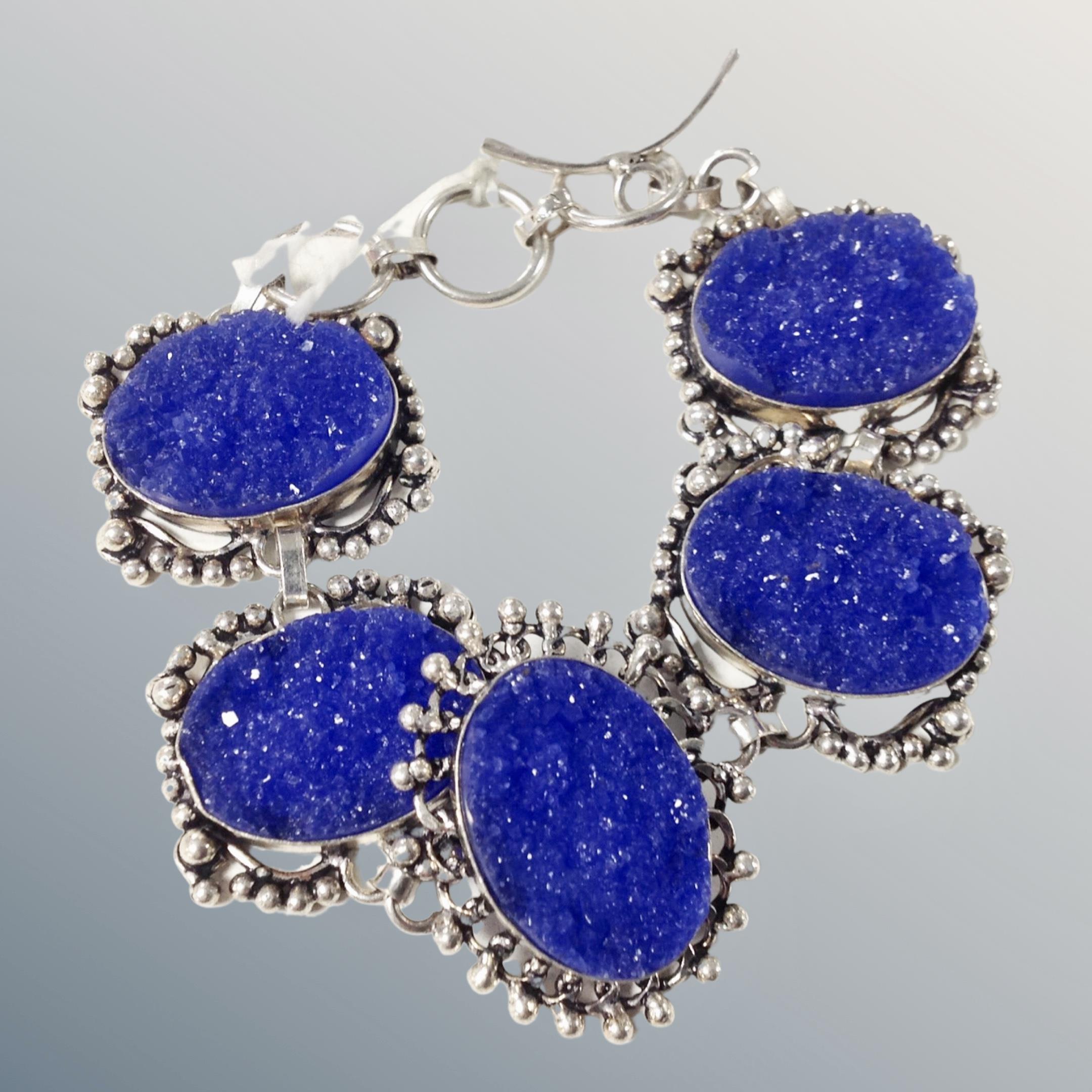 A silver bracelet with five ornate panels of rough blue stones, 34g.