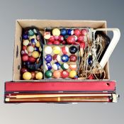A box containing cased snooker cue, quantity of assorted pool balls, triangles, pool table pockets,