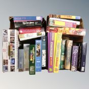 Two boxes containing a quantity of assorted jigsaws to include Horrible History, board games.