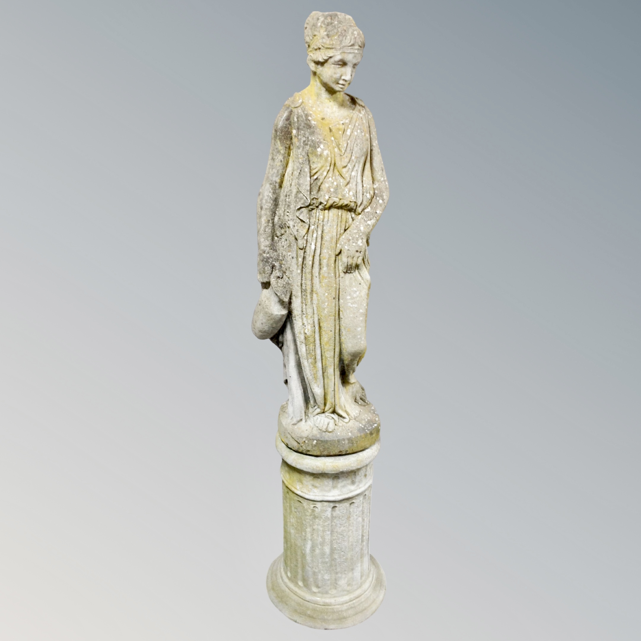 A concrete statue of a Greek woman carrying an urn on plinth,