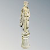 A concrete statue of a Greek woman carrying an urn on plinth,