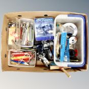 A box containing fishing equipment to include lures, reels, line, etc.