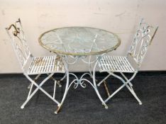 A wrought iron circular glass topped table with two chairs