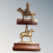 A pair of antique brass military figures on horseback, mounted on wooden stands.