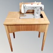 A Duet Deluxe Zigzag electric sewing machine in teak table.