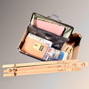 A vintage leather case containing art books together with a folding artist easel and a wooden