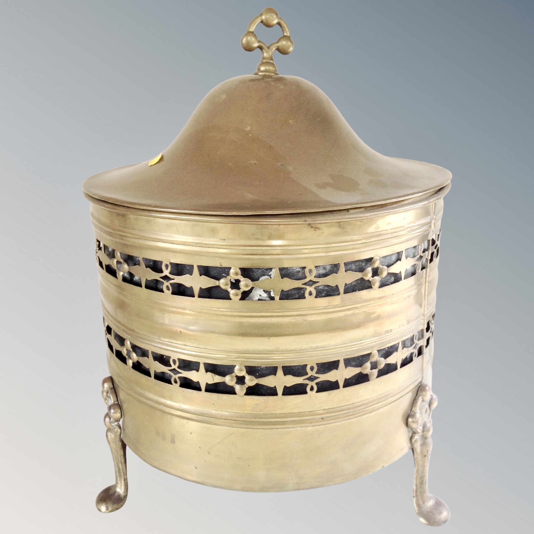 An antique brass lidded coal bucket with liner on raised feet.
