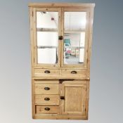 An antique pine double door glazed kitchen cabinet with cupboards and drawers beneath (no back