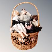 A wicker hand basket containing vintage dolls