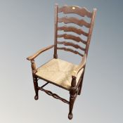 An oak Arts and Crafts ladder back rush seated kitchen armchair