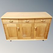 A 20th century Ercol triple door sideboard fitted with three drawers