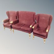 A three piece wingback lounge suite in Burgundy fabric