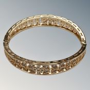 A yellow metal bangle with flower and leaf pattern, unmarked.