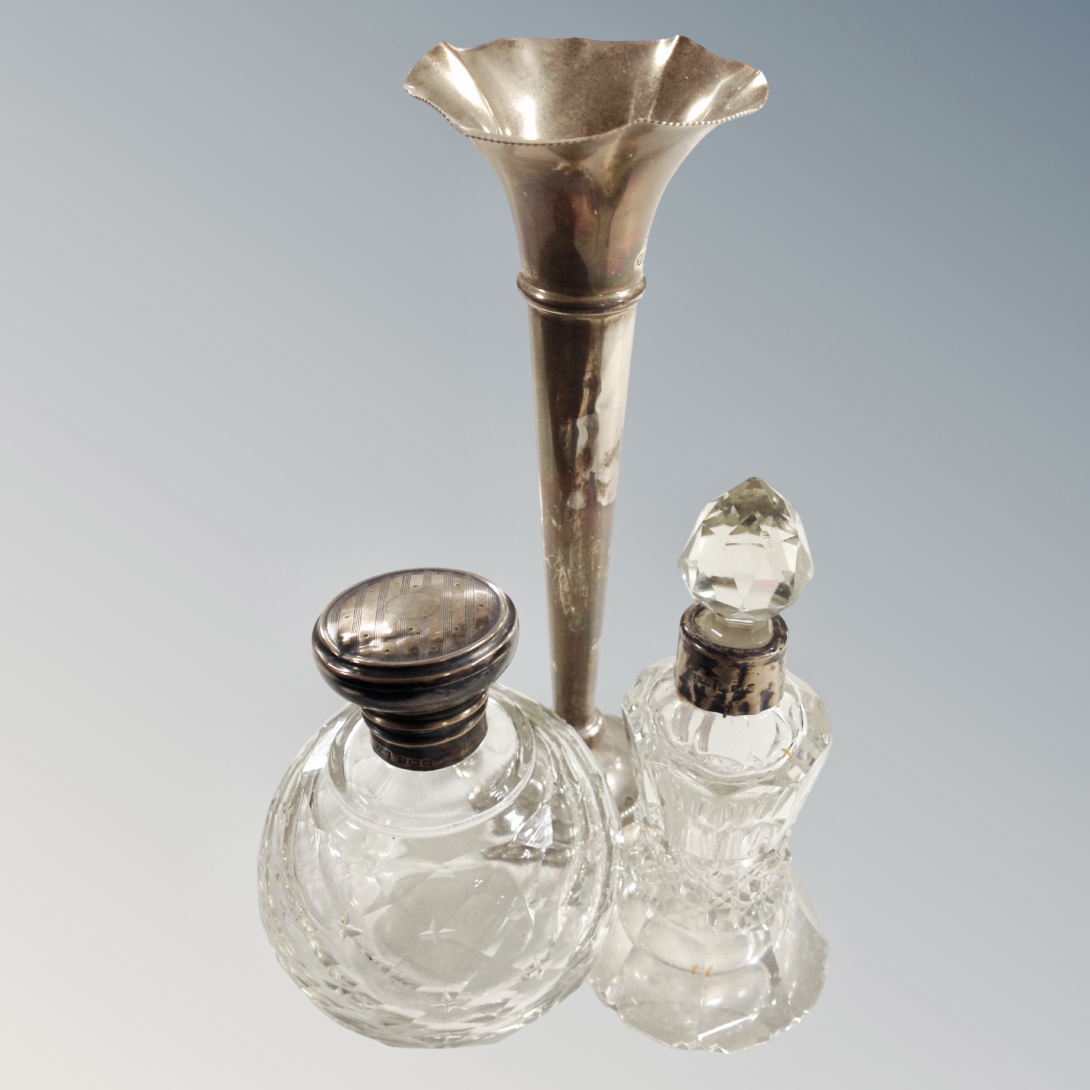 A silver topped dressing table jar, similar perfume bottle and a loaded silver trumpet vase.
