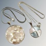 A silver and mother of pearl disc pendant on chain, another similar.