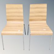 A pair of contemporary bent plywood dining chairs on metal legs.
