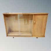 A 20th century Ercol double door sliding glass bookcase, fitted cupboard, on castors,