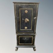An antique cat iron safe with keys on a painted wooden stand.