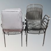 A set of four metal stacking garden armchairs, three with cushions.