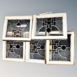 A box containing five Victorian stained glass leaded windows in frames.