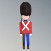 A painted wooden figure of a soldier wearing a bearskin,