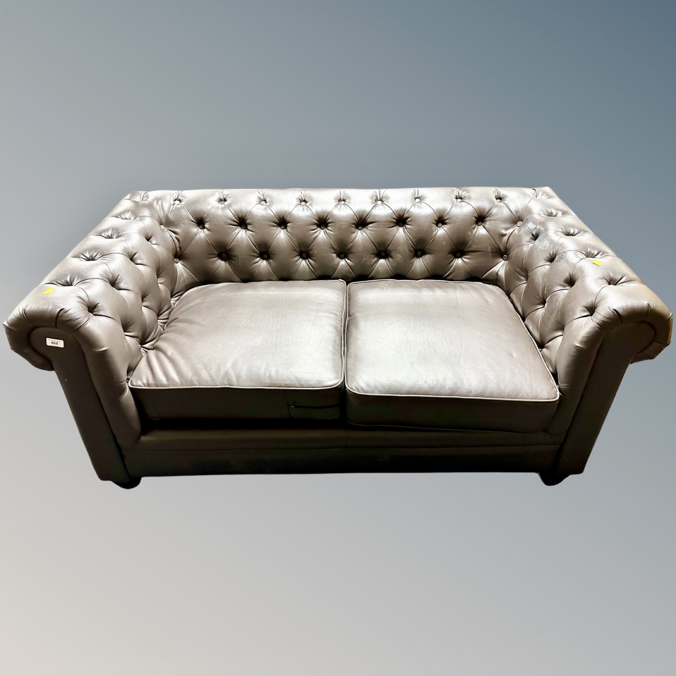 A two seater Chesterfield club settee upholstered in brown vinyl.