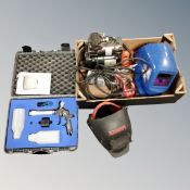 A box containing mini compressor with accessories, welding masks, a Easy coat, spray system in case.