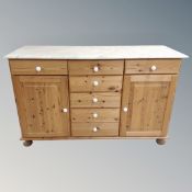 A pine double door sideboard fitted seven drawers with marble top, porcelain handles,