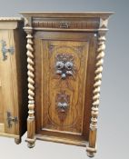 A 19th century carved oak single door cabinet with barley twist column supports,