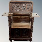 A heavily carved hardwood oriental style cocktail cabinet, 81cm by 40cm by 95cm when closed.