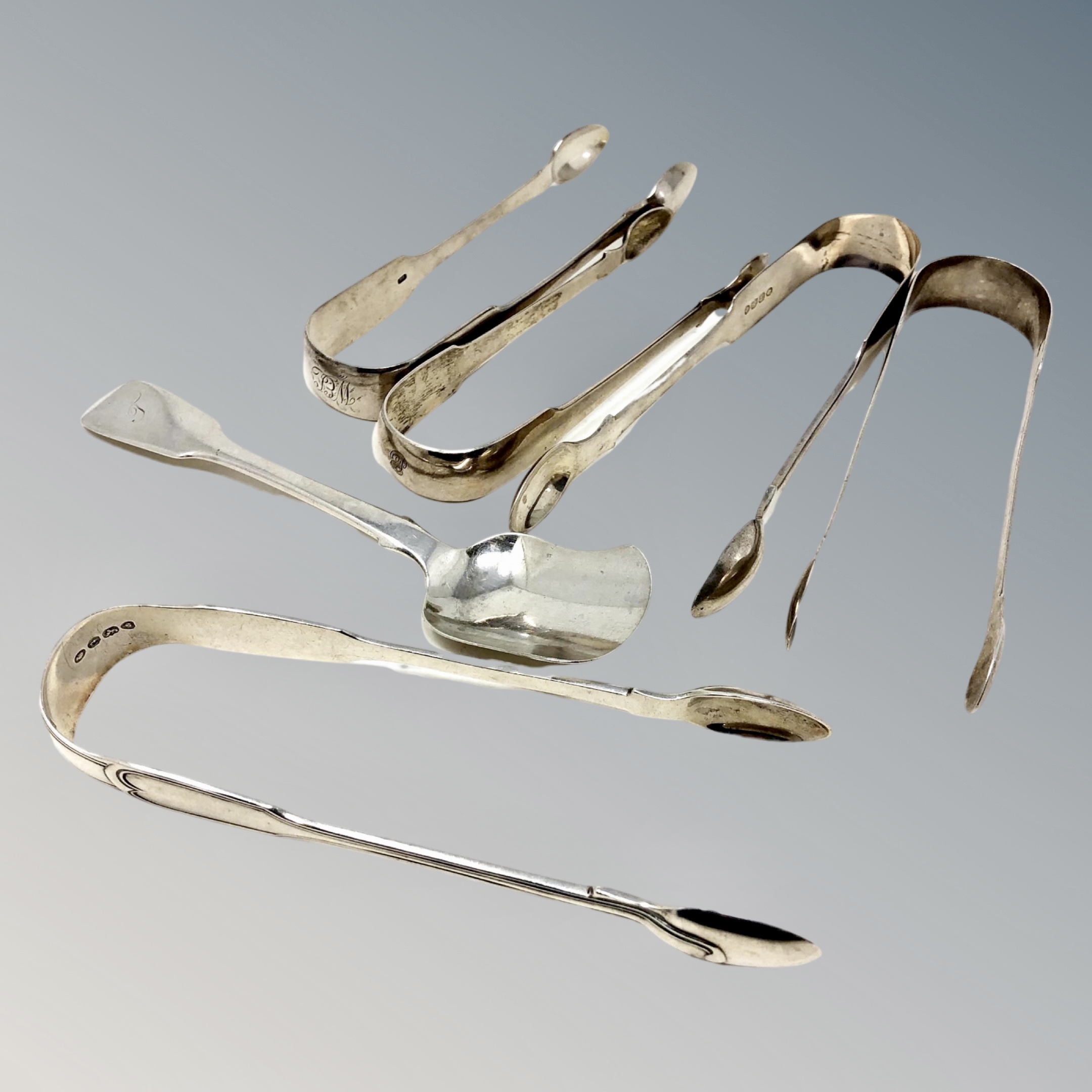 Five pairs of Georgian/William IV sugar tongs and a spoon,