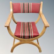 A Danish blonde oak X-framed open armchair upholstered in a striped fabric.