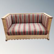 An early 20th century Danish heavily carved oak framed hall settee upholstered in a striped fabric,