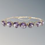 A gold and amethyst bracelet, the seven amethysts in raised claw settings,