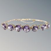 A gold and amethyst bracelet, the seven amethysts in raised claw settings,