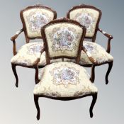 A set of three carved beech French style salon armchairs upholstered in a tapestry fabric.