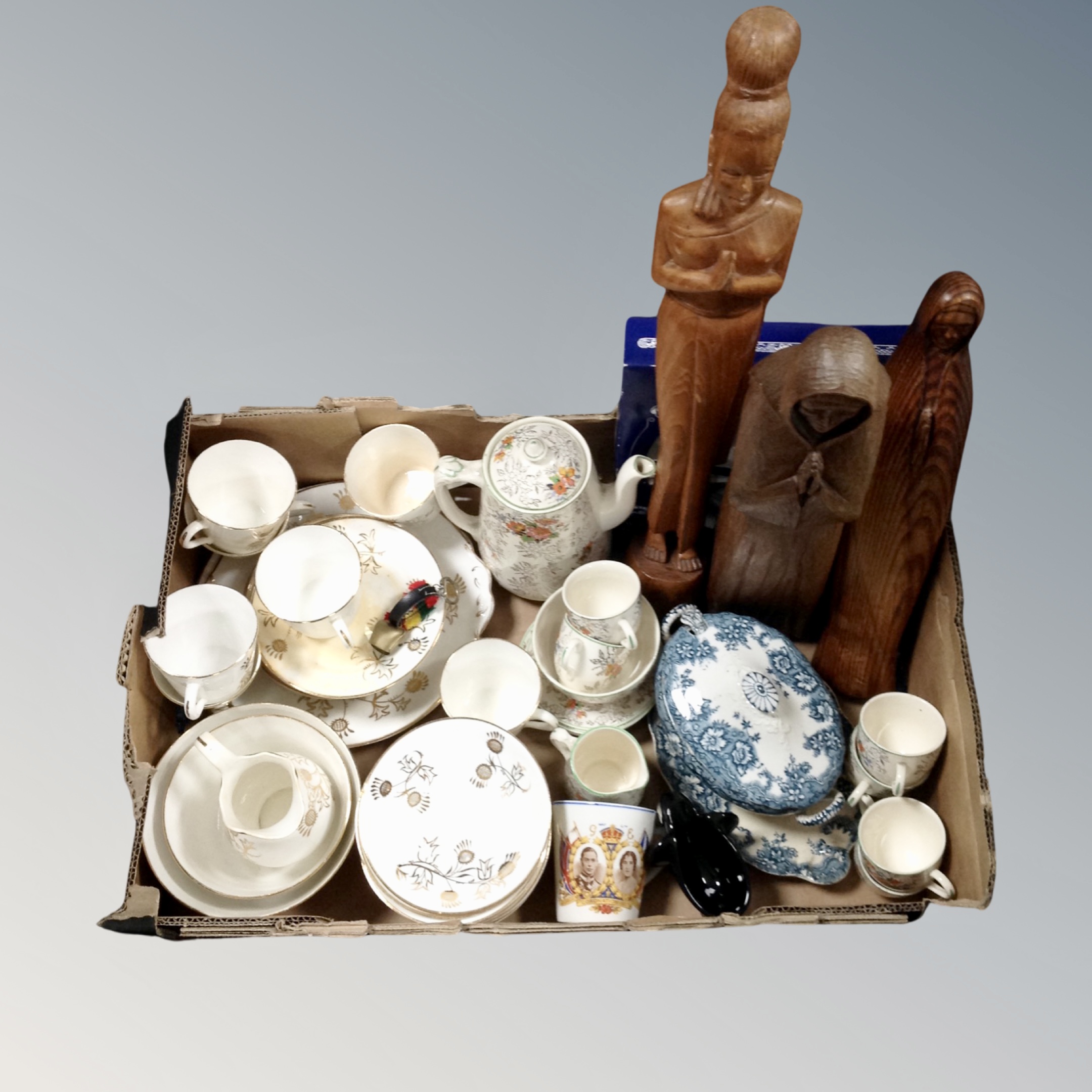A box containing antique and later teaware, commemorative mug, carved wooden figures etc.