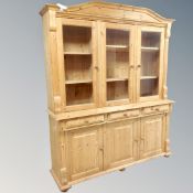 A pine farmhouse triple door glazed bookcase fitted with cupboards and drawers beneath.