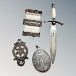 A silver bookmark in the form of a dagger and three medals/decorations.